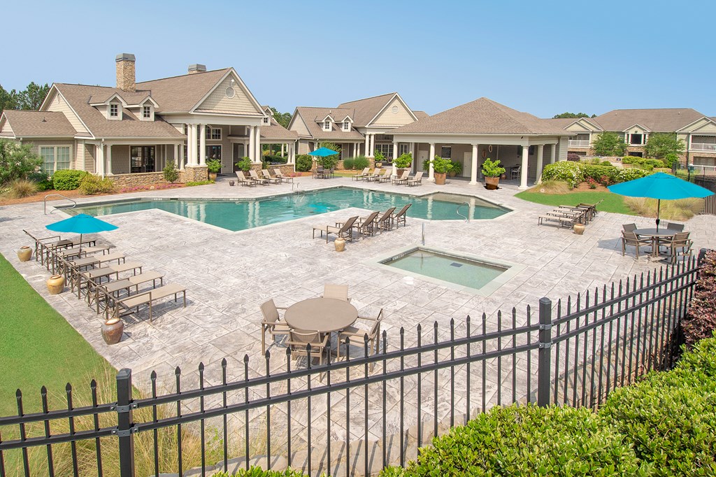 a swimming pool with tables and umbrellas in front of a house