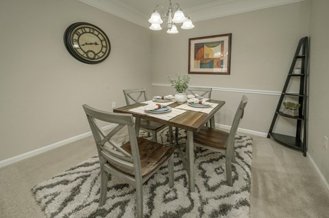 A dining room with a table set for two and a clock on the wall.