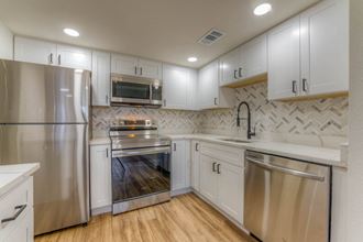 a kitchen with white cabinets and stainless steel appliances