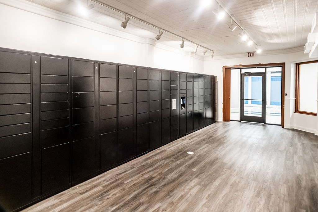 a row of black lockers in a white room with a door