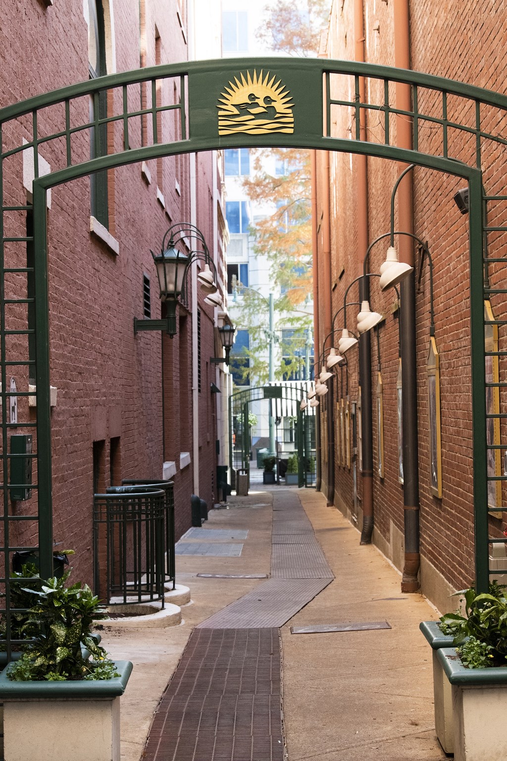 an alleyway between two brick buildings with a green archway over the street