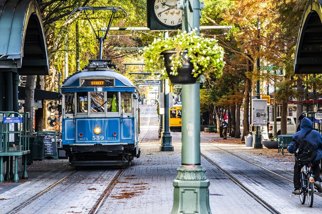 a blue trolley train traveling down a city street