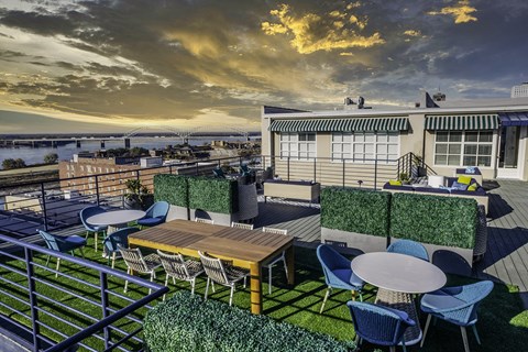 a rooftop terrace with tables and chairs and a view of the ocean