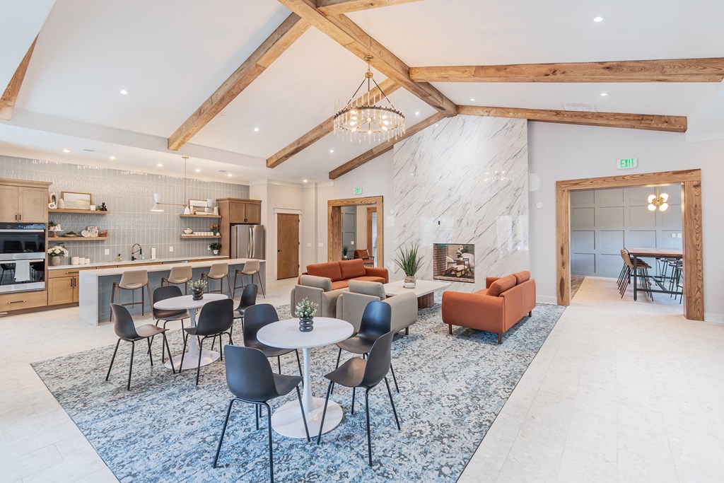 a communal area with tables and chairs and a living room with a fireplace