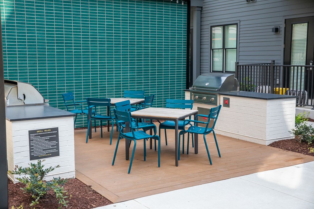 A patio with a table and chairs and a grill.