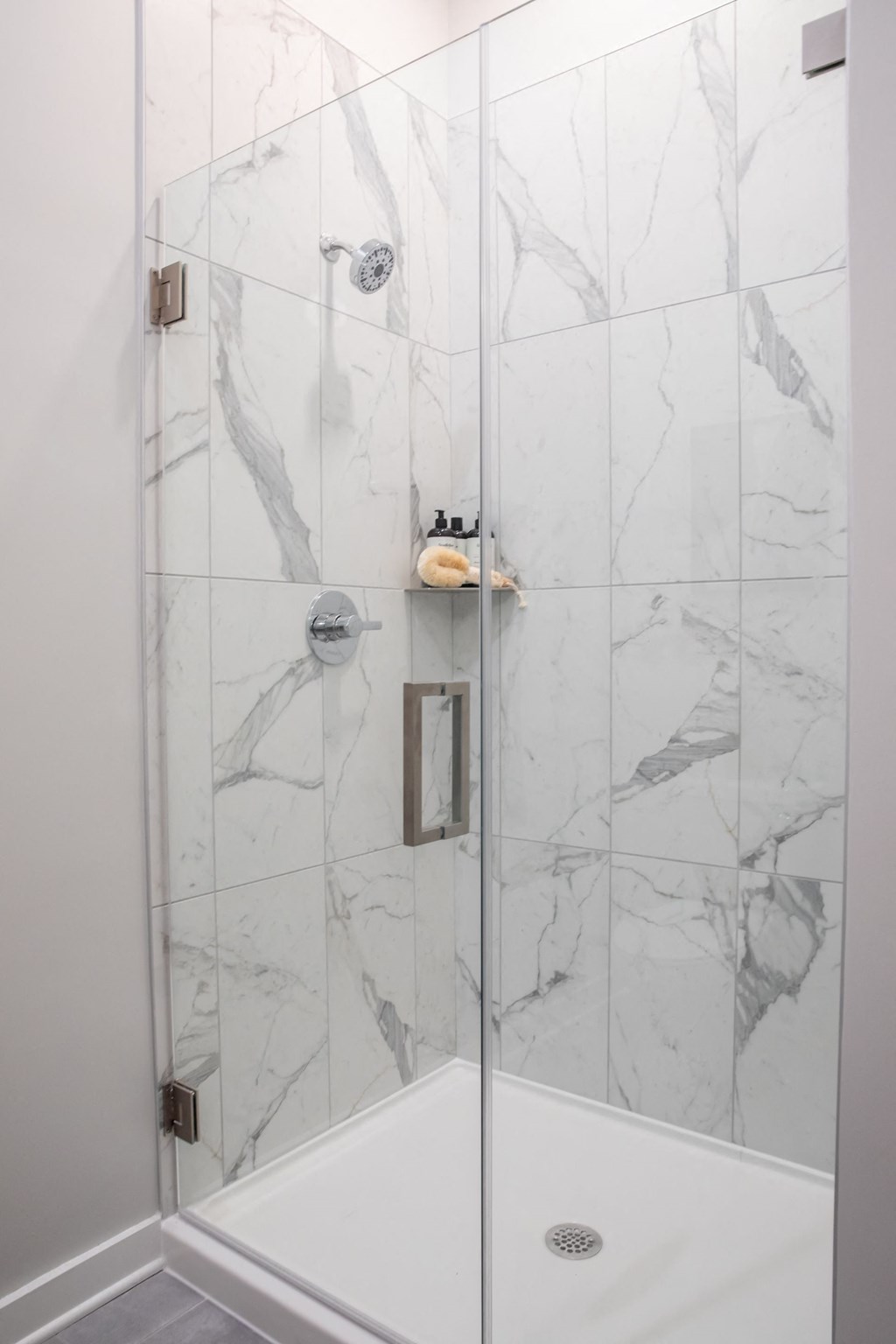 A white shower with a marble tile wall.