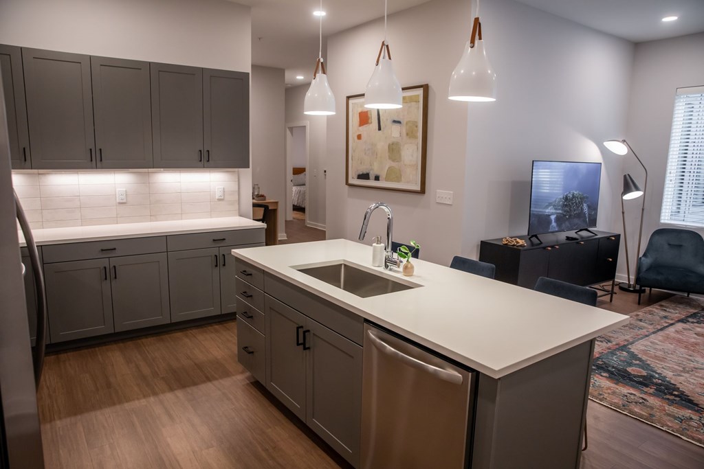 A kitchen with a white counter top and grey cabinets.