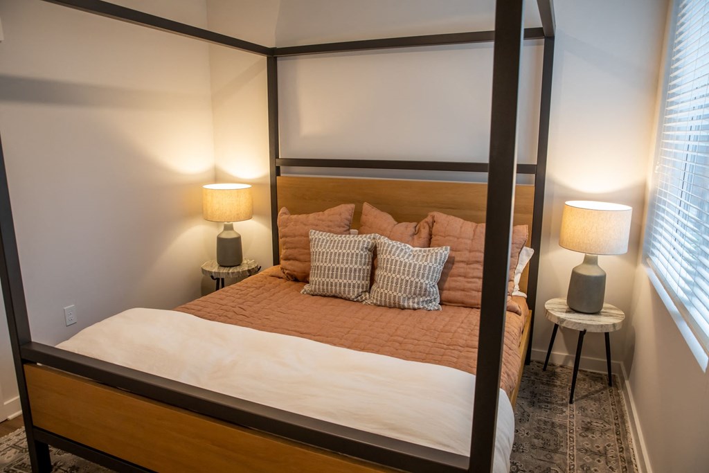 A bed with a brown headboard and white bedding is in a room with two lamps on side tables.