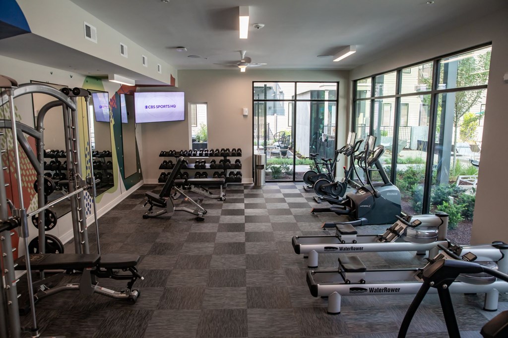 A gym with a variety of equipment including treadmills, weights, and exercise machines.