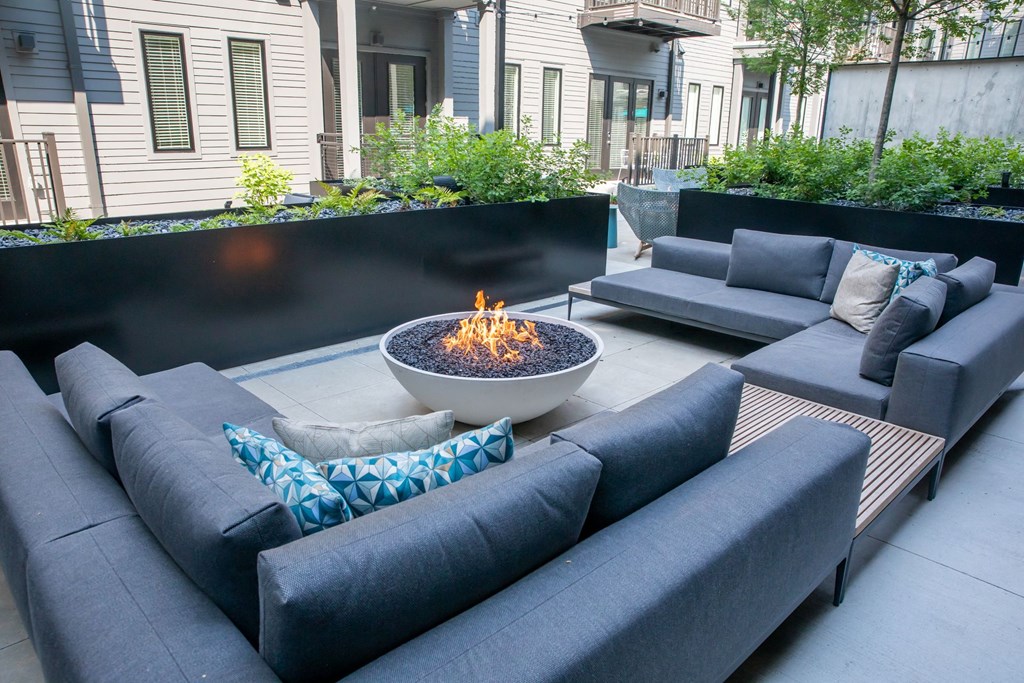 A modern outdoor seating area with a fire pit in the center.