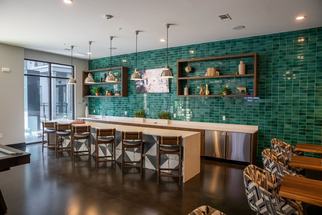 A modern kitchen with a green tiled backsplash and wooden furniture.