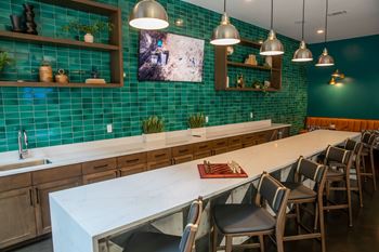 A kitchen with a long white counter and green tiled walls.