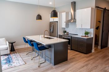 A kitchen with a white island and blue chairs.