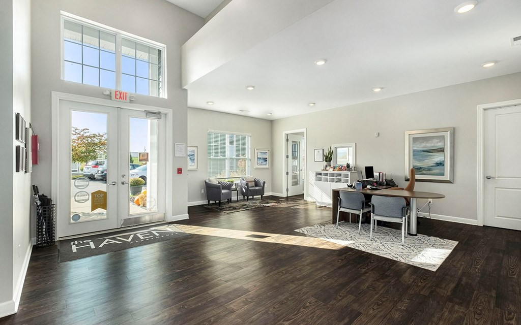 A spacious room with a wooden floor and a white rug in the center.