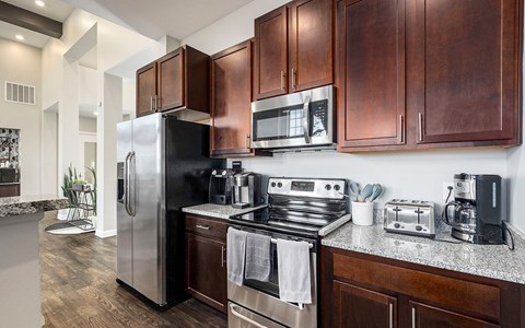 A modern kitchen with dark wood cabinets and stainless steel appliances.