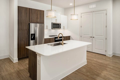 a kitchen with a white counter top and a stainless steel refrigerator