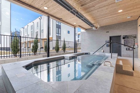 Bozeman, MT Townhomes with In-Unit Washer and Dryer - Highmark Bozeman - Covered Spa With Clear Water, Handrail Entry, Wood Ceiling, Black Fencing, And Modern Townhome Buildings Nearby.