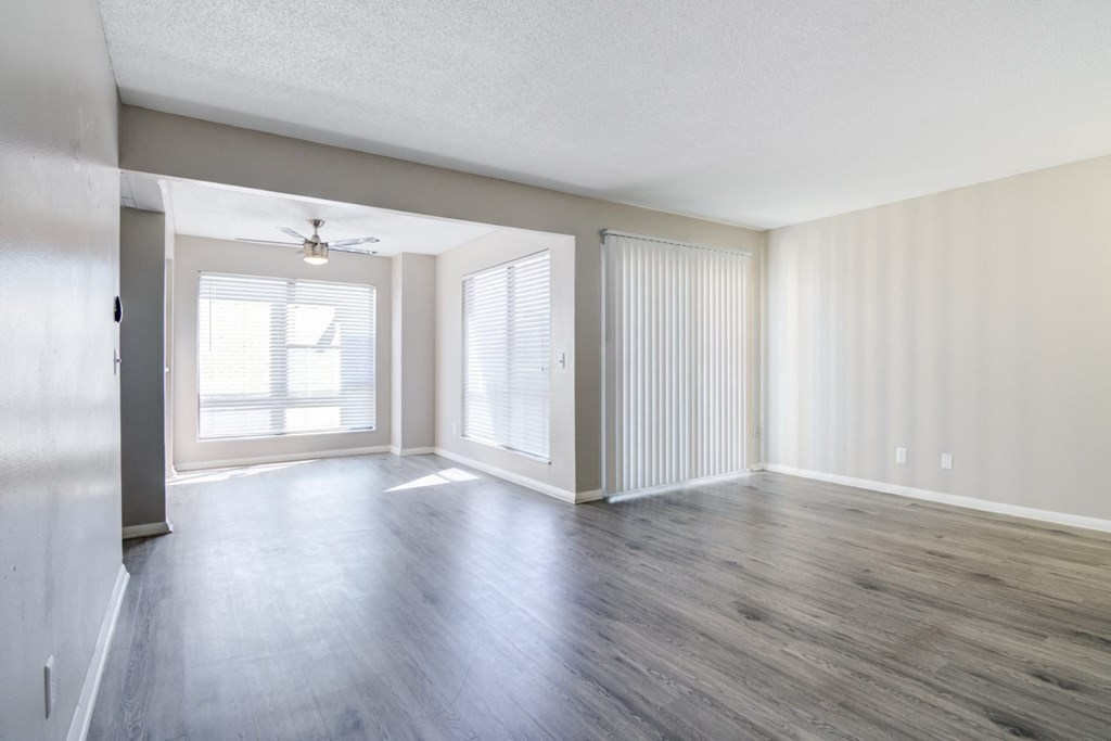 an empty living room with wood floors and a ceiling fan