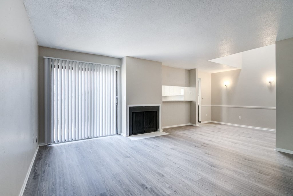an empty living room with a fireplace and sliding glass doors