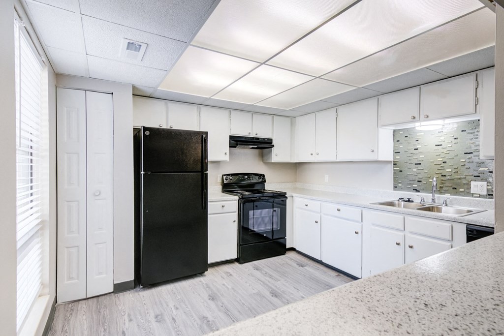a kitchen with white cabinets and a black refrigerator