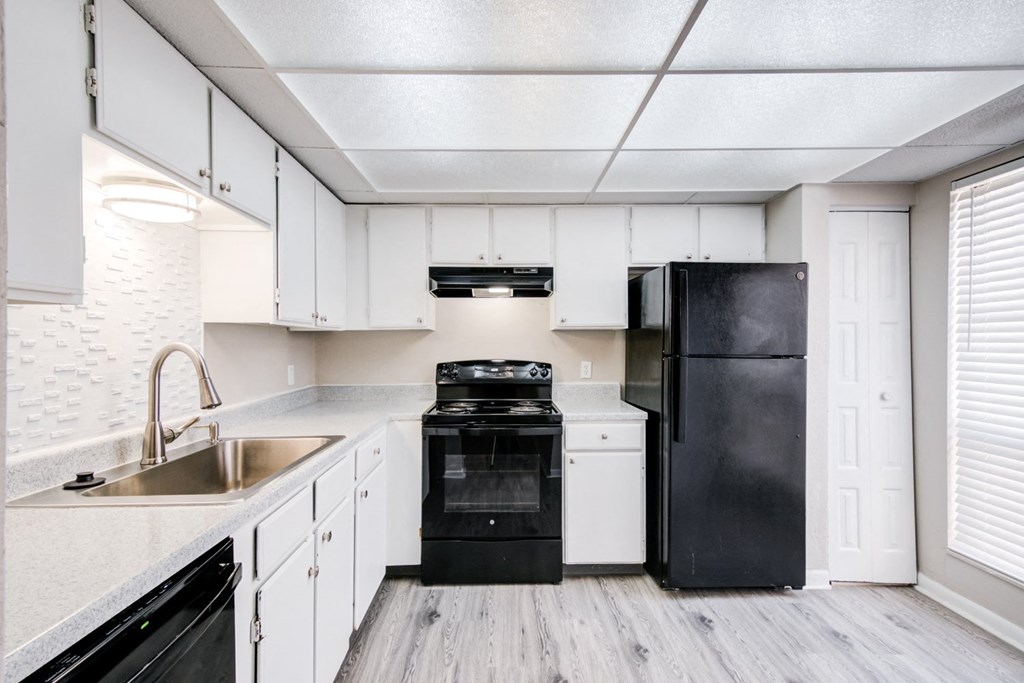 an empty kitchen with black appliances and white cabinets