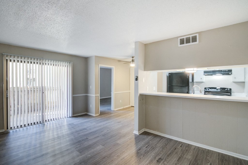 an open living room and kitchen with wood flooring and a large window