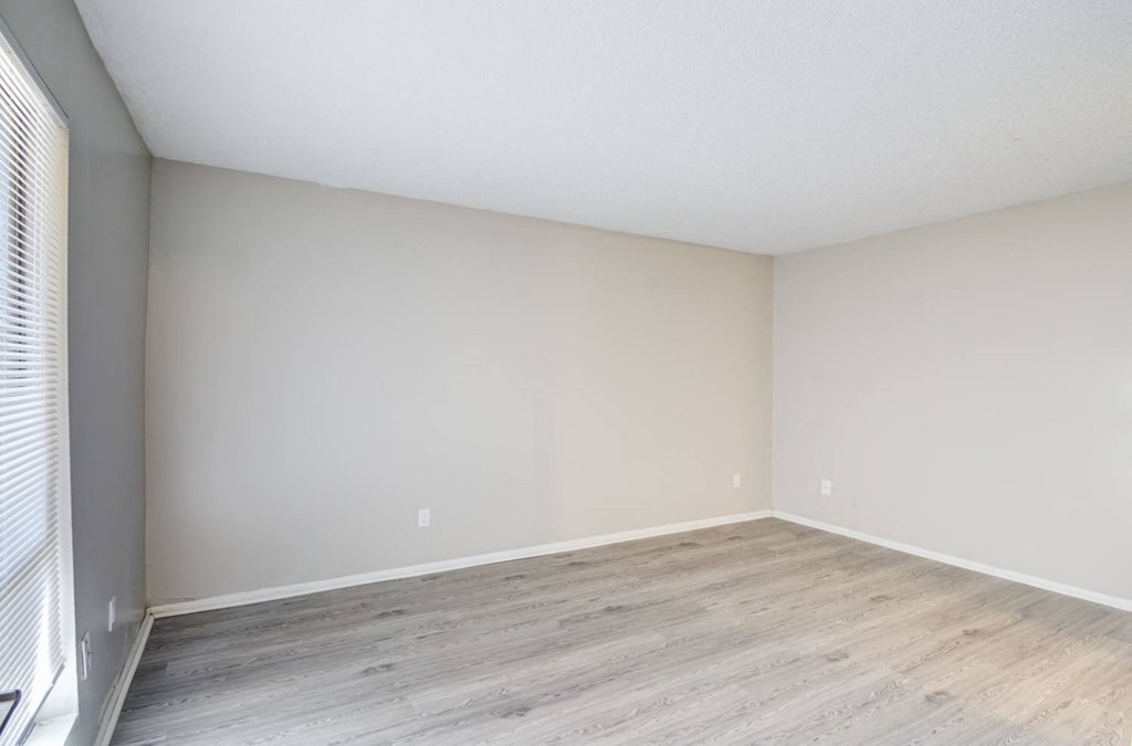 an empty room with wood floors and white walls