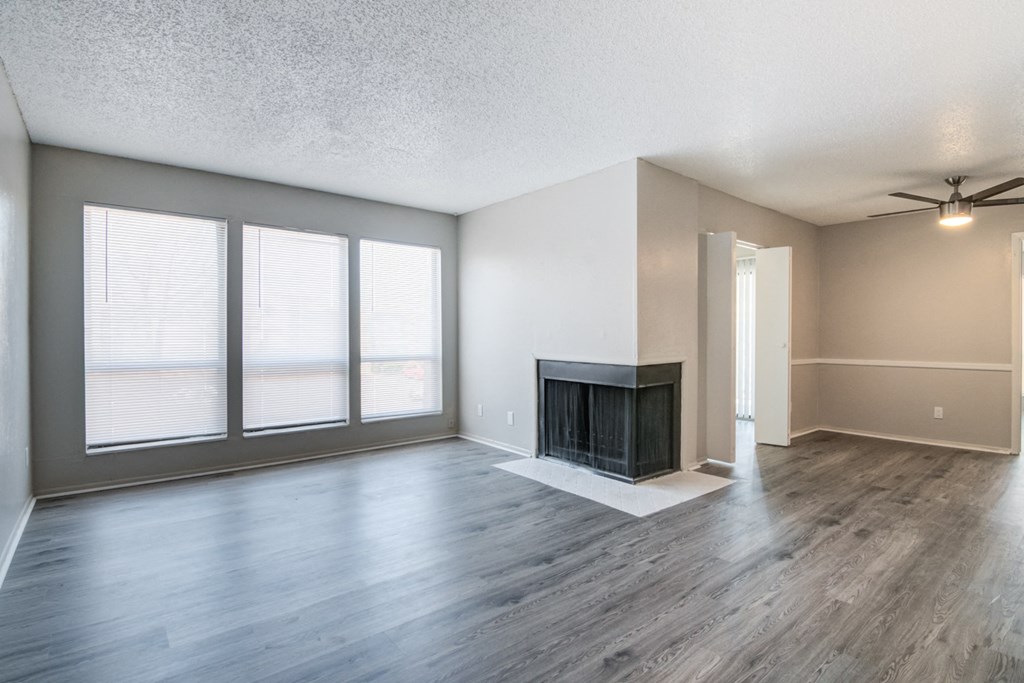 an empty living room with a fireplace and windows