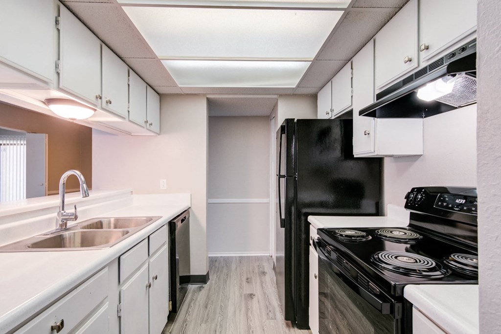 an empty kitchen with white cabinets and black appliances