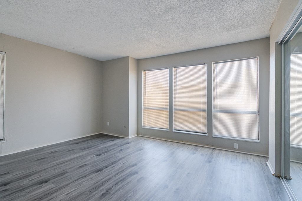 the spacious living room with large windows and wood flooring