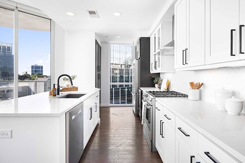 A modern kitchen with white cabinets and a view of the city.