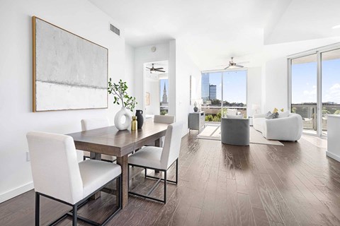 A modern dining room with a wooden table and white chairs.