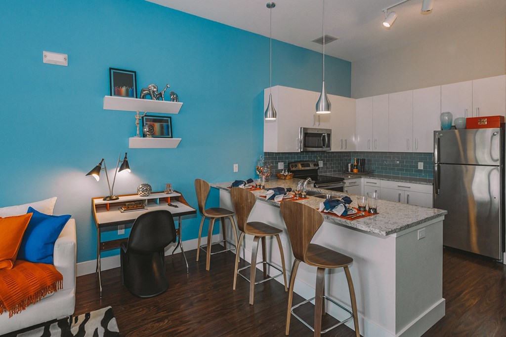 a kitchen with a bar and a blue wall and a stainless steel refrigerator