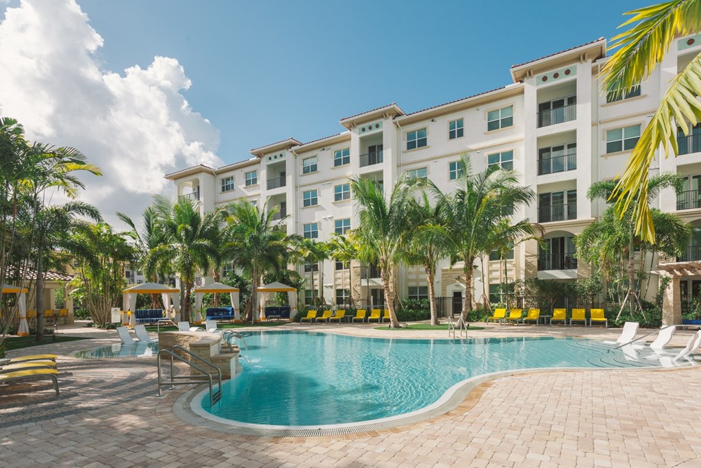 a swimming pool in front of a hotel with palm trees