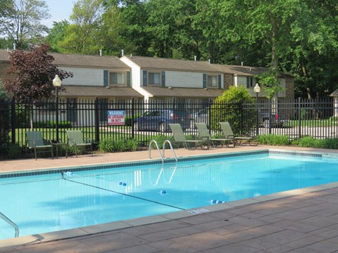 A pool with a diving board in front of a house.