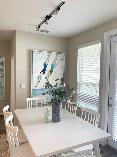 a dining room with a table and chairs and a painting on the wall