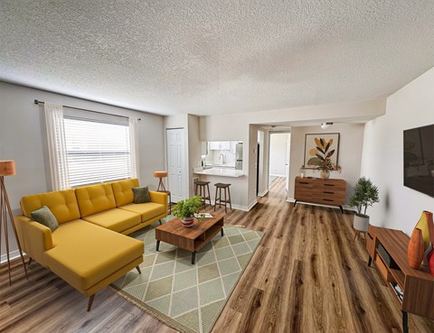 A living room with a yellow sofa and a wooden floor.