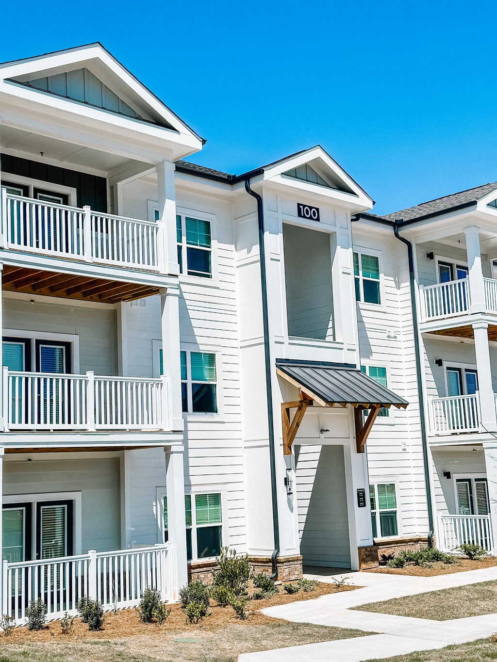 an apartment building with white siding and a walkway