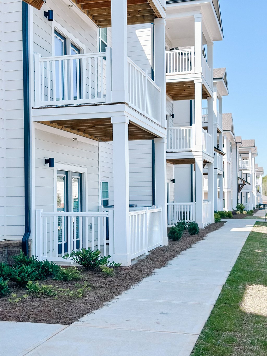 a row of white houses with balconies and a sidewalk