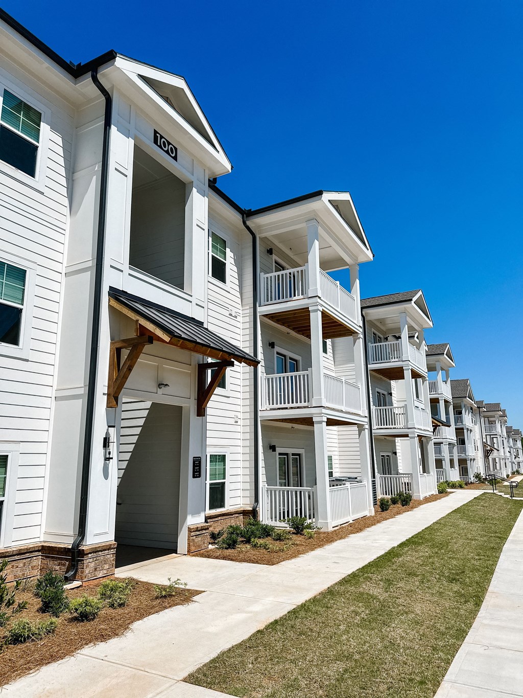an exterior view of an apartment building with a sidewalk