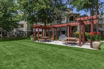 a grassy area with picnic tables and a pergola