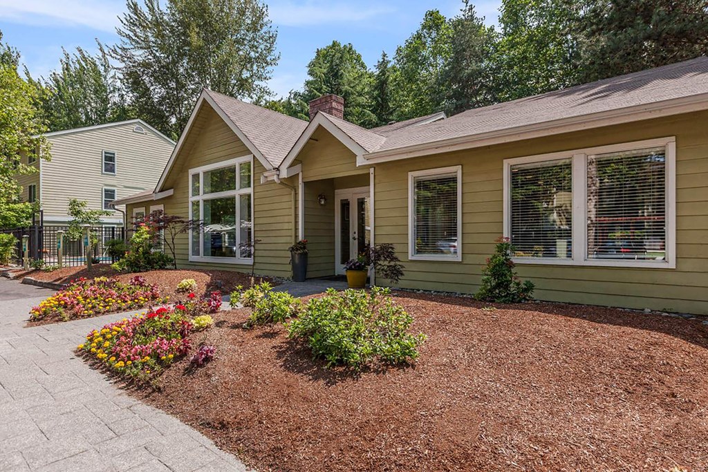 a house with a driveway and flowers in front of it