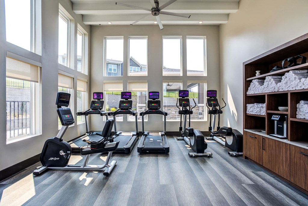 four treadmills in the fitness center atrium of a building with windows
