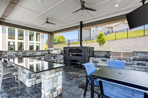A modern outdoor kitchen with a stone counter and a grill.