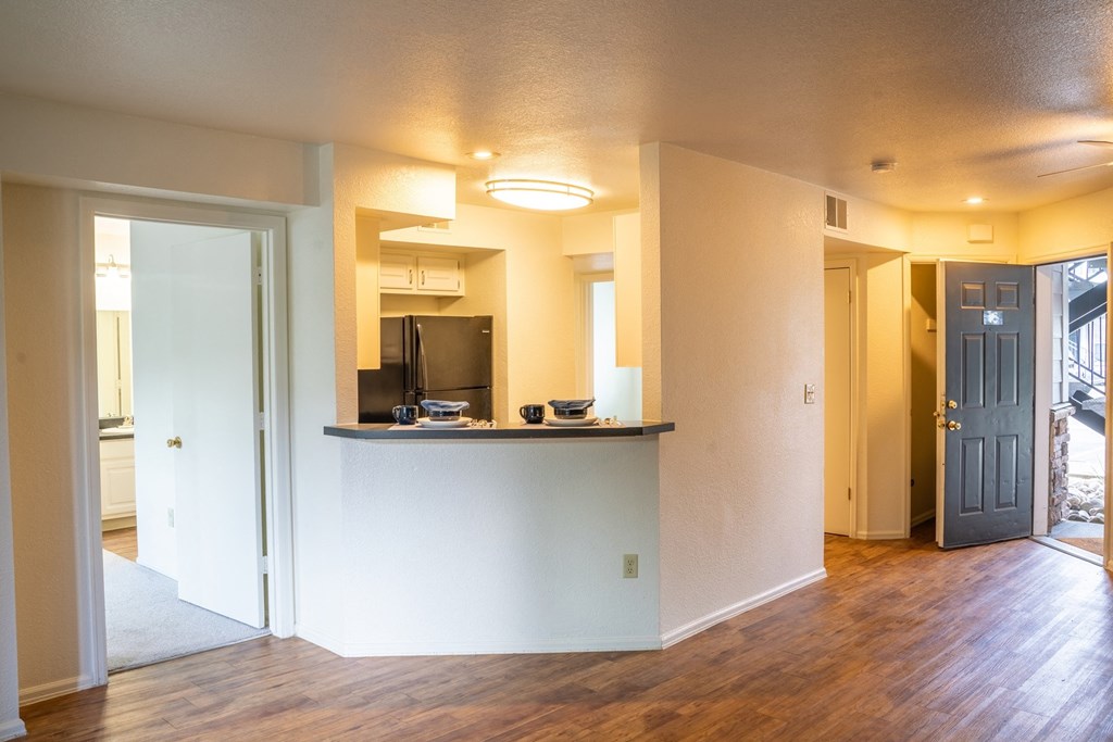 an empty living room with a kitchen and a door
