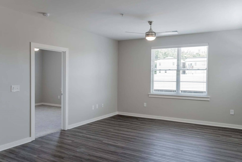 A room with a ceiling fan and a window with blinds.
