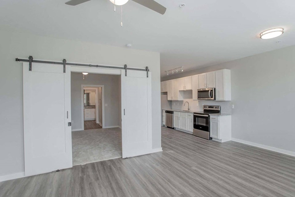 A room with a sliding door and a kitchen area in the background.