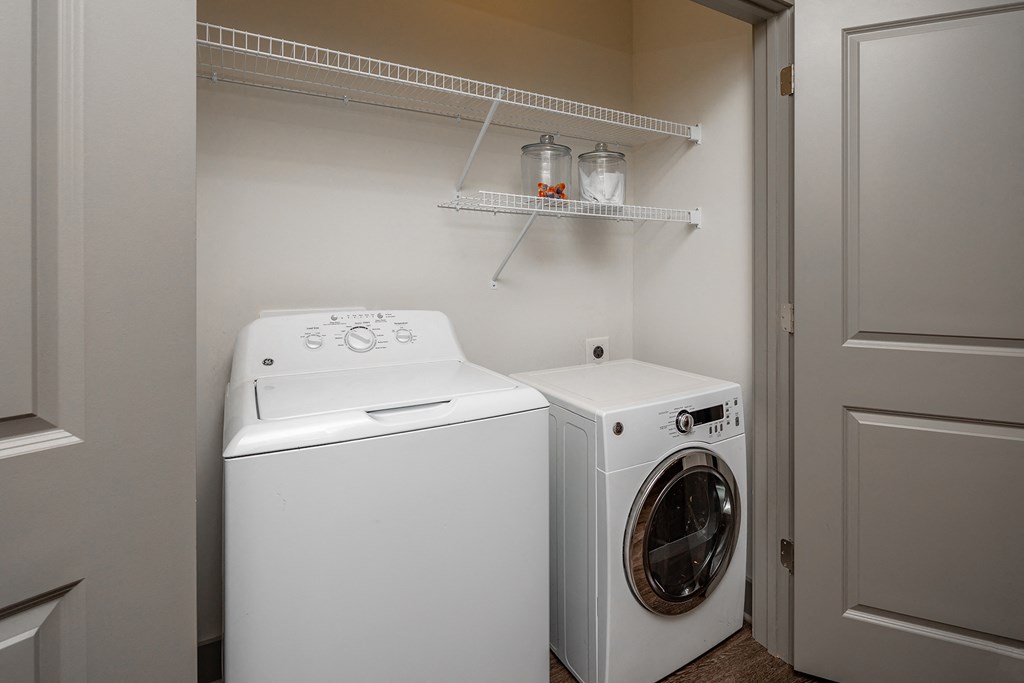 a washer and dryer in a small laundry room with a shelf above it