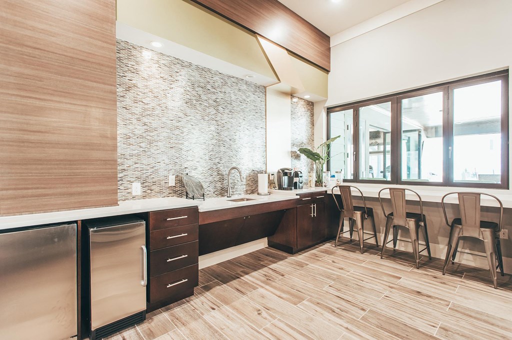 a kitchen with a counter and chairs in front of a window