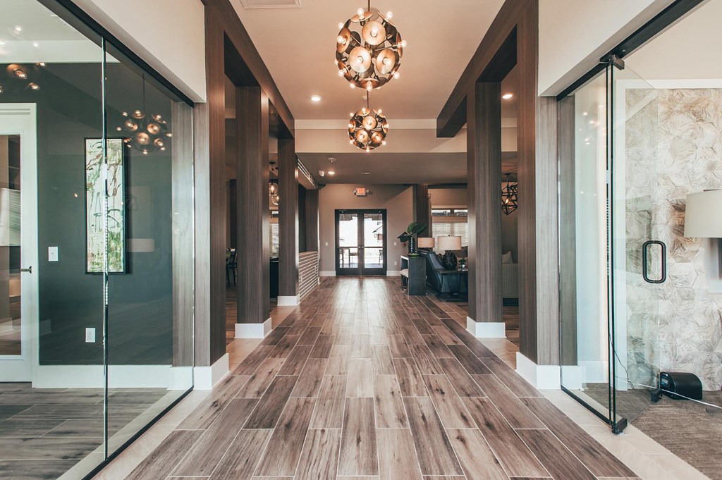 a long hallway with glass doors and a chandelier